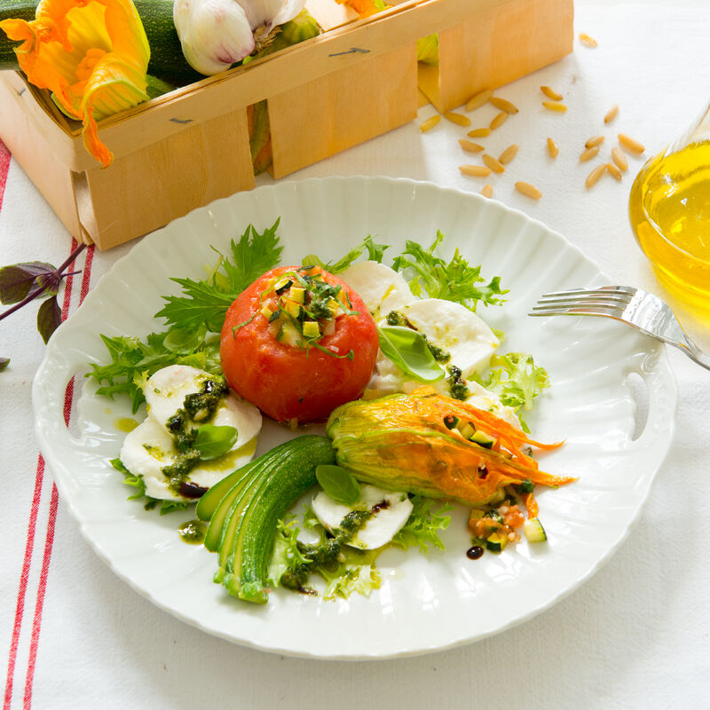 Gefüllte Tomaten und Zucchiniblüten auf Büffelmozzarella mit Basilikum-Essenz
