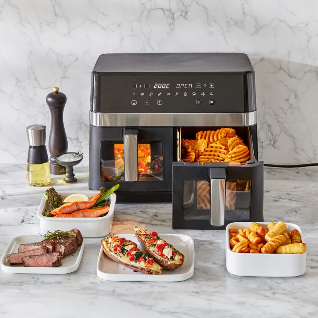 Digitale Doppel-Heißluftfritteuse mit zwei Schubladen, serviert mit Steak, Gemüse und Pommes.