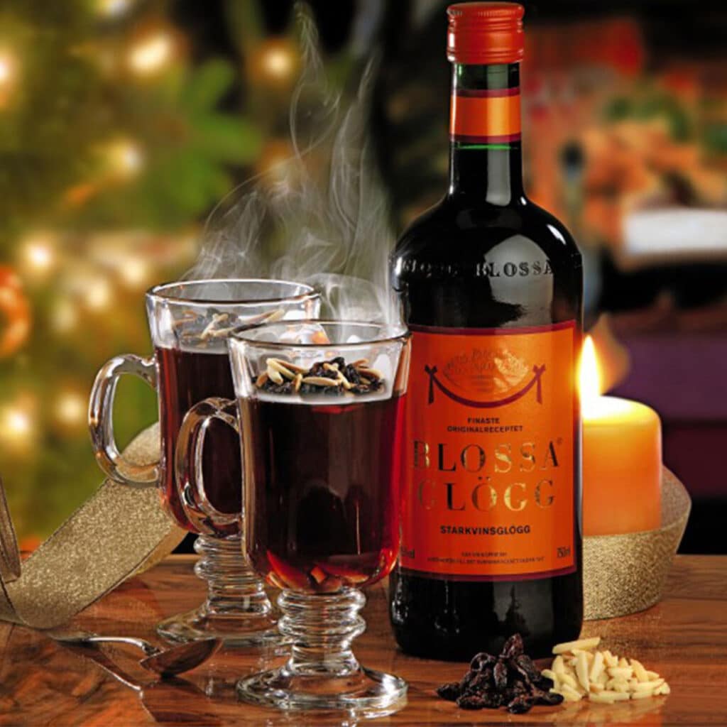 Blossa Glögg Glühwein mit zwei dampfenden Gläsern, Mandeln und Rosinen, weihnachtlich serviert