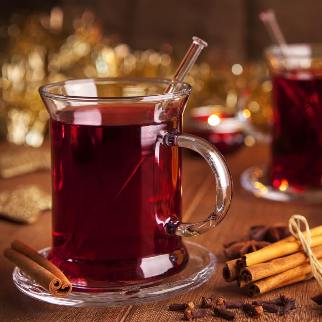 Glühwein im Glas mit Zimtstangen und Gewürznelken, festlich dekoriert