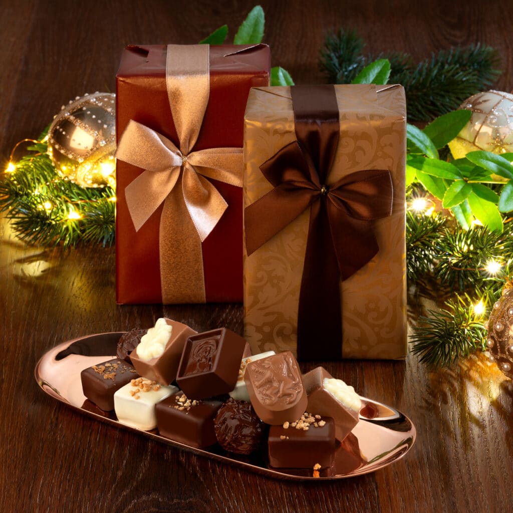 Festliche Geschenkverpackung mit Pralinenmischung aus Vollmilch, Zartbitter und weißer Schokolade auf Tablett