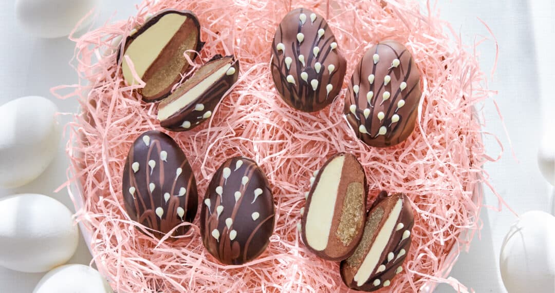 Gef&uuml;llte Schokoladeneier mit heller und dunkler Cremef&uuml;llung in rosa Osterk&ouml;rbchen-F&uuml;llmaterial